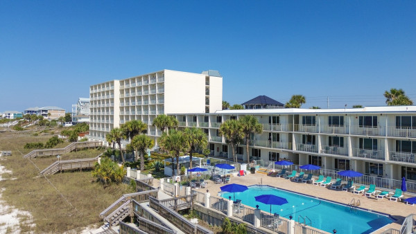 A large white building with a pool and lounge chairs in front of it.
