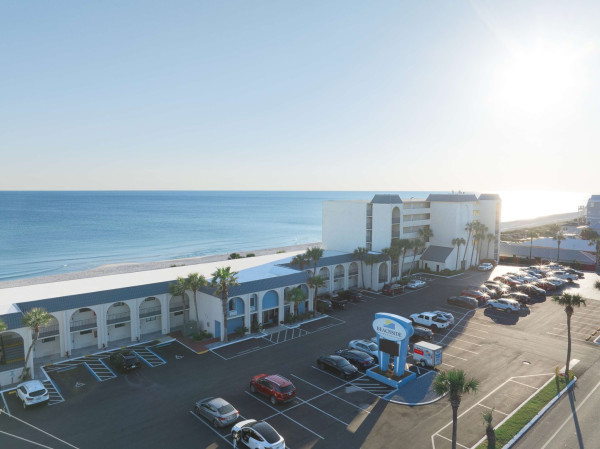 A wide-angle view of a beachfront hotel with a parking lot in front of it.